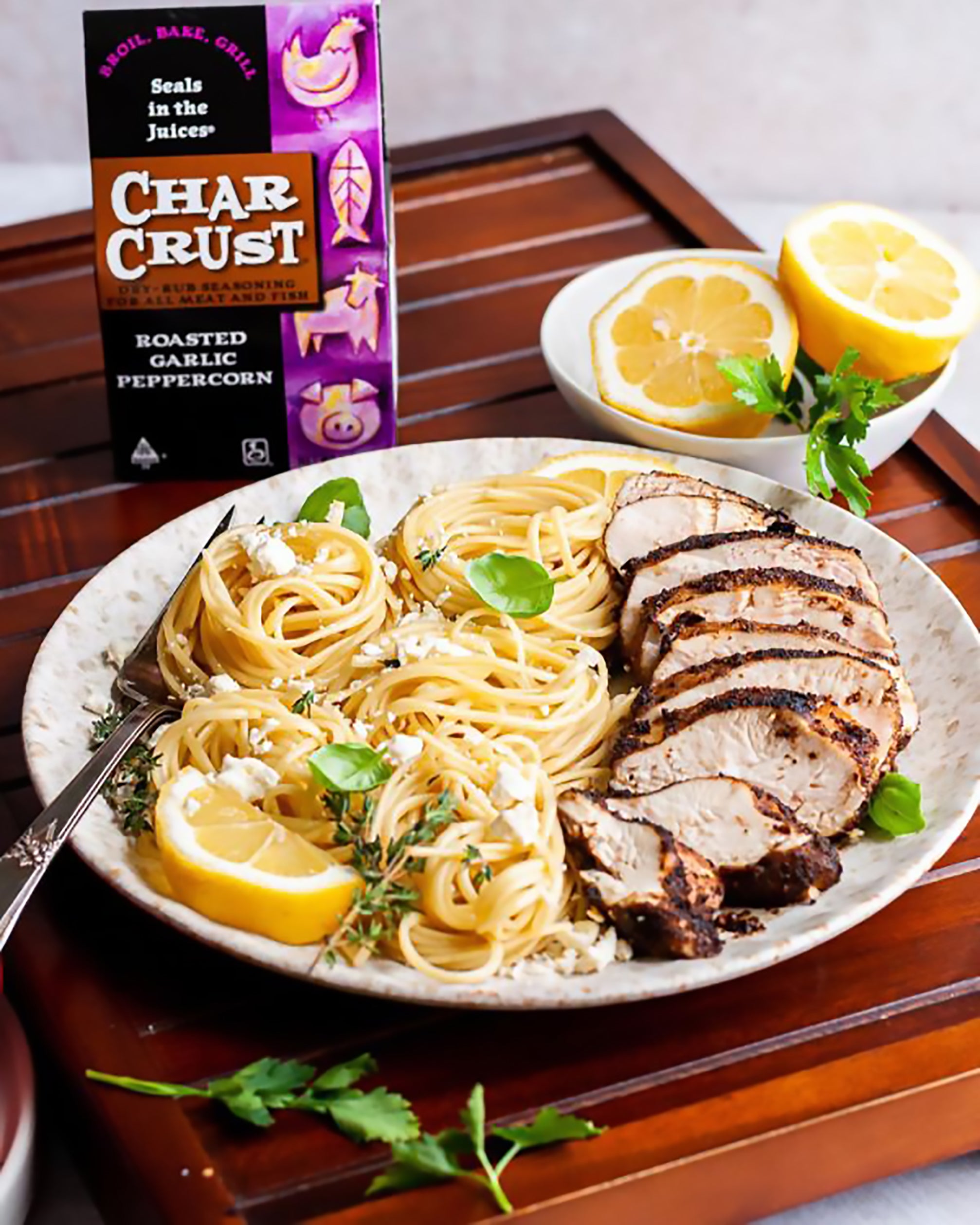 Pasta with feta and basil. Char-Crusted chicken sliced on the side. Lemons on the side. Roasted Garlic Peppercorn package in the background.